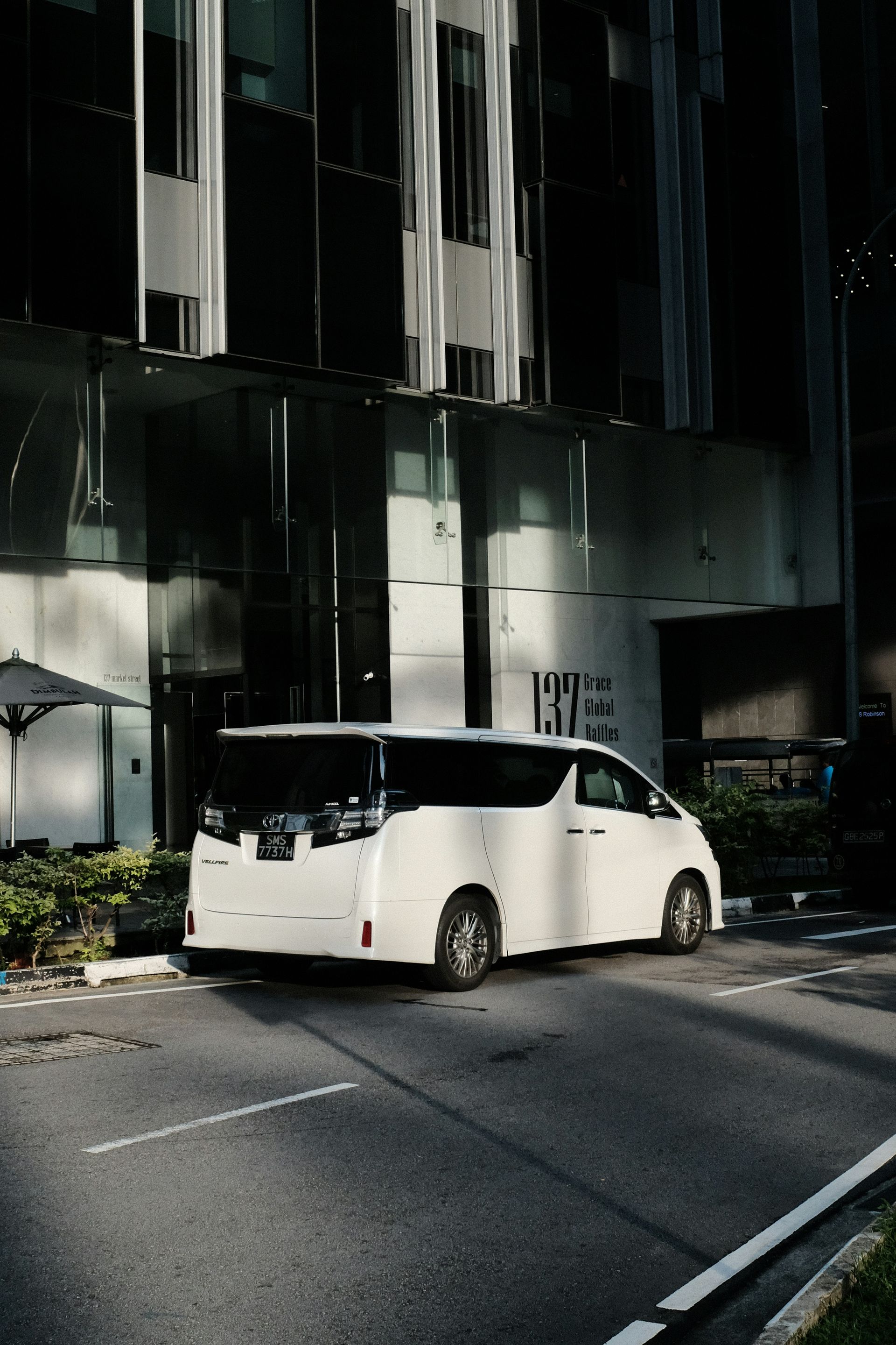 a white bus parked in front of a tall building