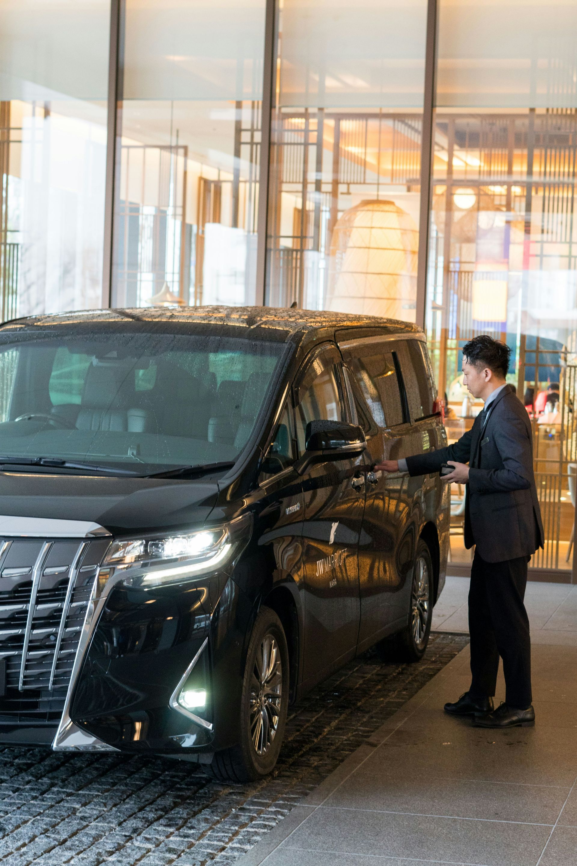 A man in a suit standing next to a black car