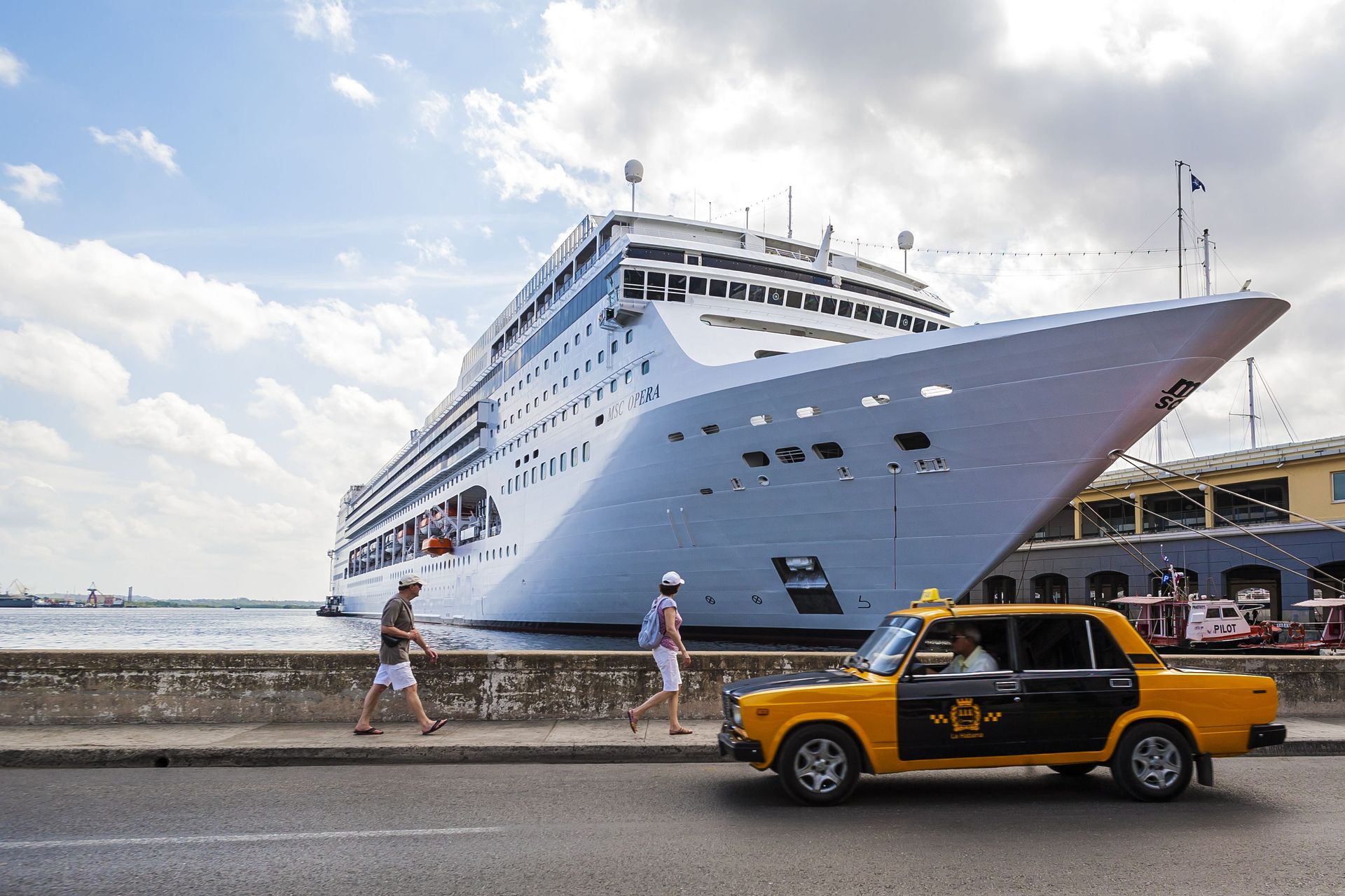 A classic Cuban taxi drives past a cruise ship docked in Havana, Cuba.